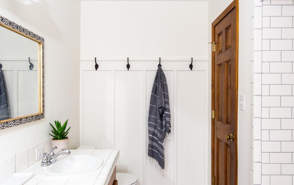 На свободной стене в ванной сделали декоративные планки из дерева с крючками для полотенец. Этот простой прием очень преобразил комнату